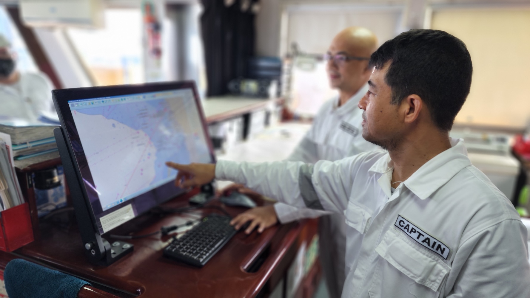 Filipino ship captain leading crew on the bridge of a vessel